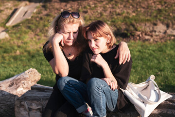 Naklejka premium A woman hugs a teenage daughter after a long conversation about teenage problems, the mother is upset and the daughter thinks, she has hope in eyes, she now sees a way out of problems
