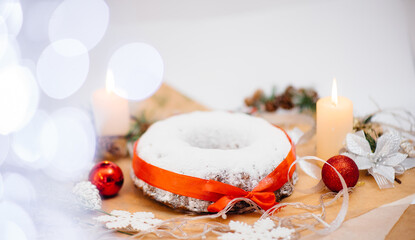 Traditional round Christmas stollen made of dried fruits and nuts sprinkled with powdered sugar on...