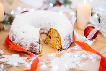 Traditional round Christmas stollen made of dried fruits and nuts sprinkled with powdered sugar on...