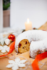 Traditional round Christmas stollen made of dried fruits and nuts sprinkled with powdered sugar on...