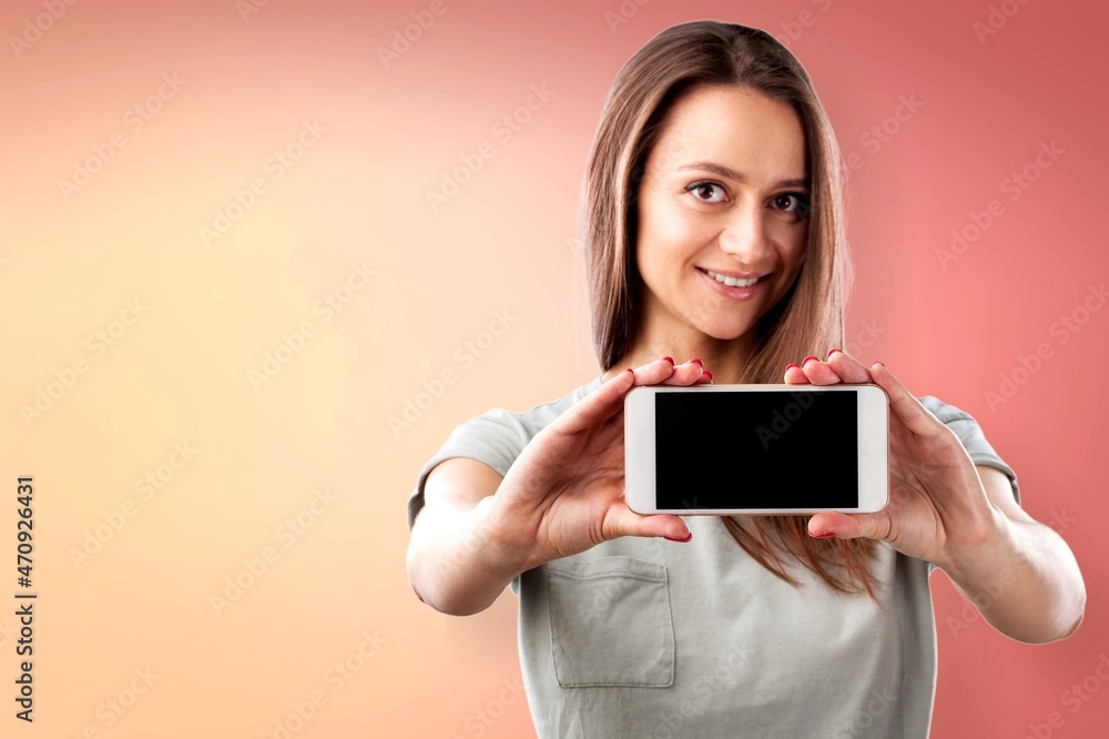 Poster Excited and surprised young woman holding smartphone with blank screen in hand