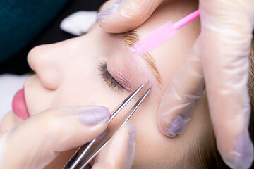 close-up of the eyebrows after the lamination procedure, the master tweezers to pluck the hairs