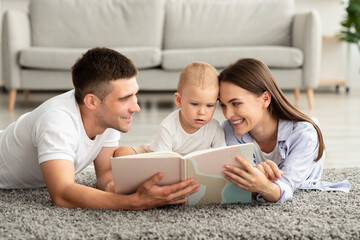 Early Education For Kids. Parents Reading Book To Their Cute Toddler Son