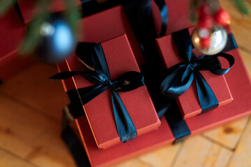 Christmas gifts under a snowy tree, beautiful red boxes. Gift for the new year. Beautiful box with a bow. Dark background.