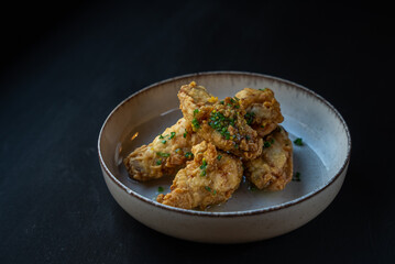 Roasted chicken wings in white plate. Copy space. Tasty snack for beer on a dark background. Modern cuisine