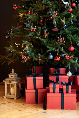 Christmas gifts under a snowy tree, beautiful red boxes. Gift for the new year. Beautiful box with a bow. Dark background.