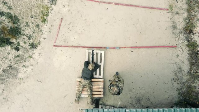 Aerial Top view of a sniper aiming at a target with an assistant. Military preparation for war. A sniper lying down aims at a target.