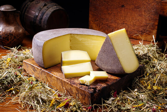 Traditional aged mountain cheese of the Alps offered as loaf and piece at a rustic wooden chalet