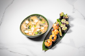 Sushi set and miso soup on white background. Maki roll for lunch offer or business lunch. Japanese traditional healthy food. KETO diet, low-carb sushi without rice. Restaurant menu. Copy space