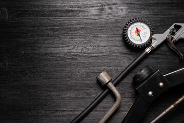 Tire fitting service concept background. Tire inflation gun, car jack and wrench on the black flat lay background with copy space.