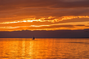 Fototapeta na wymiar Sailboat on Lake Geneva at the golden hour of sunset.