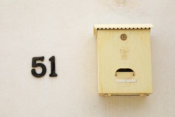 buzón amarillo metalico con el número 51 sobre una pared blanca 4M0A4552-as21