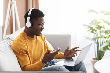 Handsome black guy having video call, using laptop at home