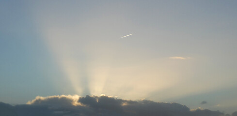 Airplane flying above the clouds. The sun is setting