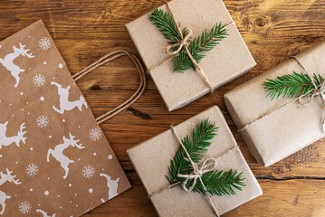 Christmas gifts wrapped in eco-friendly paper and a gift craft bag on a wooden table. Christmas flat lay. Festive background for the New Year's sale