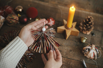 Hands holding handmade christmas angel from festive red wrapping paper on background of rustic...