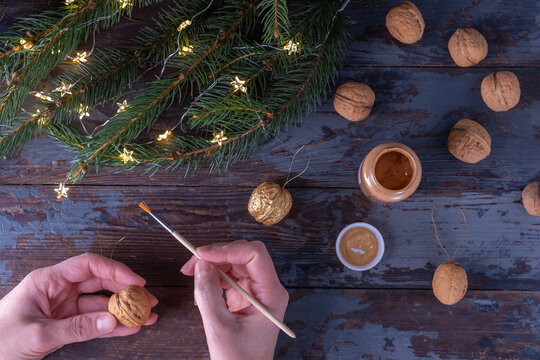 Step-by-step instructions: DIY golden nut tree toy. Step 10: Prepare the walnut with a golden loop attached to the gold paint with a paintbrush. Christmas and New Year concept.