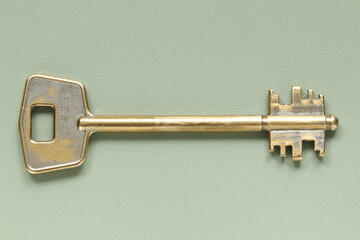 Old key from the door lock on a green background. Old key. 