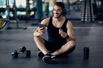 Fototapeta na wymiar Snack Break. Smiling Young Arab Man Resting At Gym After Training