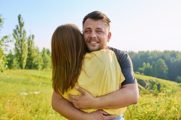 Portrait of happy adult hugging couple on summer sunny day