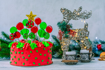 Christmas cake decorated with Christmas tree. Deer with a flashing Christmas garland. Decoration for the holiday. Beautifully served table for the celebration. Copy space.