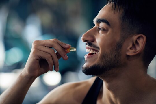 Portrait Of Happy Sportive Arab Man Taking Supplement Pill Capsule