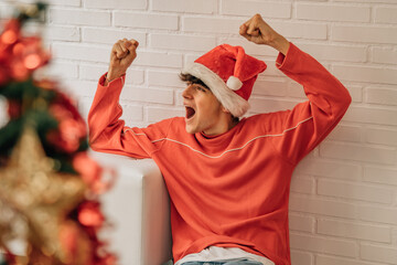 teen boy at home with santa hat euphoric and cheerful for christmas