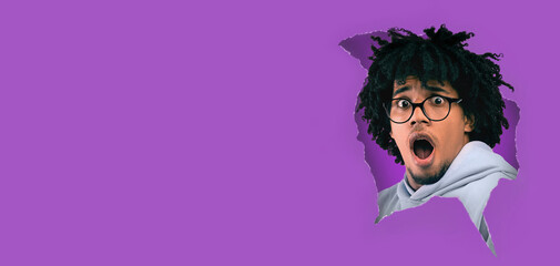 Surprised shocked black bearded man looking through paper hole