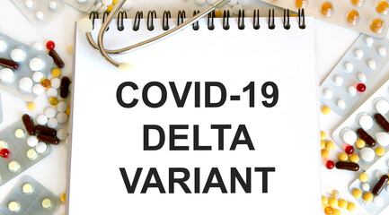 In the notebook is the text of COVID-19 DELTA VARIANT, around it are many colorful tablets.