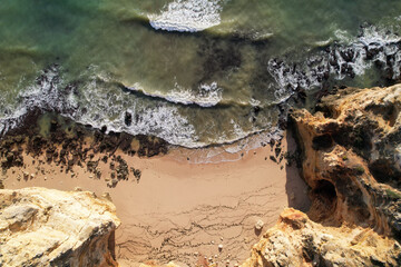 Naklejka na ściany i meble Beach and waves from top view. Turquoise water background. Summer seascape from air. Portugal Lagos Algarve. Travel concept and idea