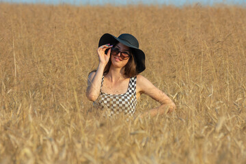 Naklejka na ściany i meble Young woman standing in wheat field