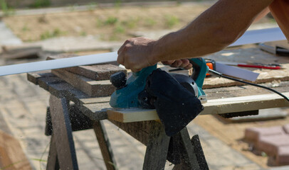 a worker processes a board with an electric plane