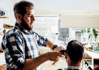 Barber cutting the client's hair. Process of trimming in the barbershop.