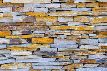 A wall of flat horizontally arranged multicolored stones.