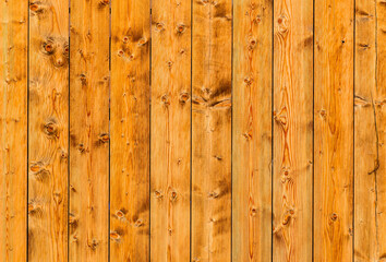Plank wall of dark yellow plates with knots and gaps