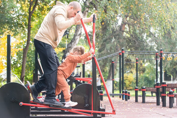 A man with his child, his little daughter, performs exercises on the sports ground of the city, the concept of an active healthy lifestyle in the family. teaching children exercises and training