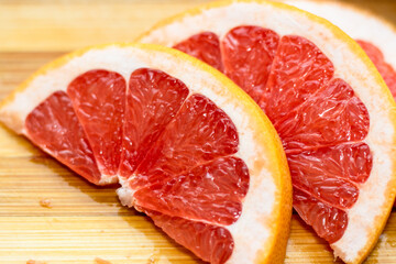 Naklejka na ściany i meble sliced pink grapefruit on a wooden board. home environment.half of a slice.healthy food,diet,slim,fit. lose weight. fibers.vitamin c from fruits red color juicy sour acrid taste