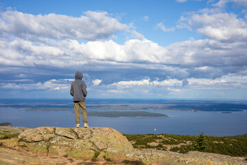 Fototapeta na wymiar Boy standing on top of a rocky mountain top