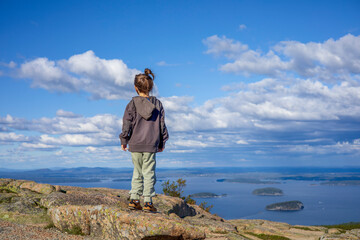 Obraz premium Little girl standing on top of a rock on a mountain
