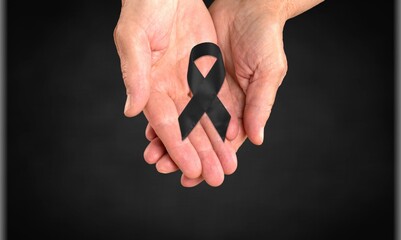 Fototapeta premium Woman hands with black funeral ribbon on dark background