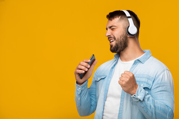 Happy mature caucasian male in headphones with closed eyes enjoys favorite music, sings on virtual...