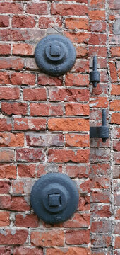 A fragment of a dilapidated brick wall with metal remnants of an old factory in Lodz. © bARTkow