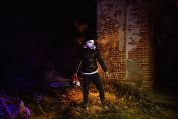 Obraz na płótnie Canvas Maniac in mask of plague doctor with chainsaw