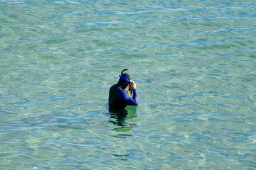 male diver with scuba gear preparing to dive in the ocean