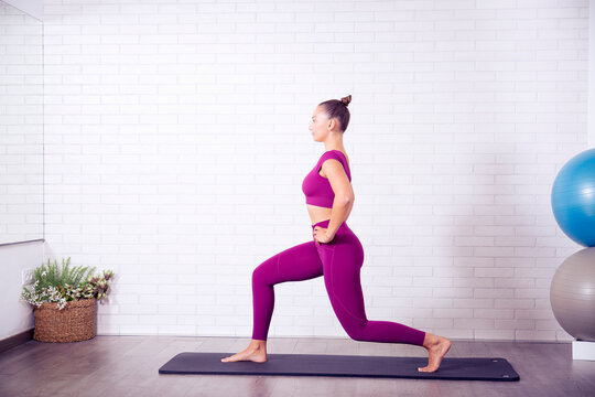 profesora de yoga y pilates mujer joven hace posiciones y posturas en un gimnasio o estudio sobre una esterilla y con un balon grande hinchable para trabajar en gimnasio ejercicios practicos