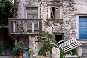 Alte Fassade mit zerfallenem Fensterladen und alter Türe mit Treppe in zerfallenem Zustand.