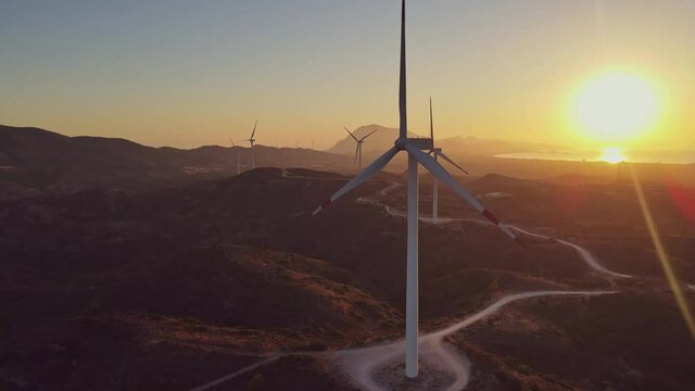 Windmills farm for power production on beautiful landscape at sunrise. Wind power turbines generating clean renewable energy