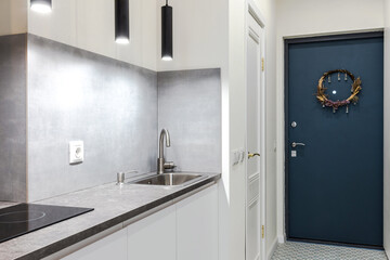 Minimalistic compact kitchen in a small apartment with elements of concrete, black and white