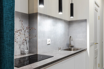 Minimalistic compact kitchen in a small apartment with elements of concrete, black and white