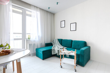 Minimalistic interior design studio apartment with white walls and a turquoise green sofa. Living room and dining room for a comfortable life
